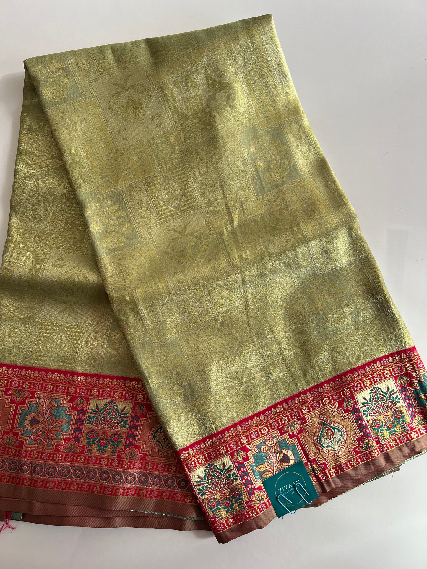 Green saree with a colorful border on a white background