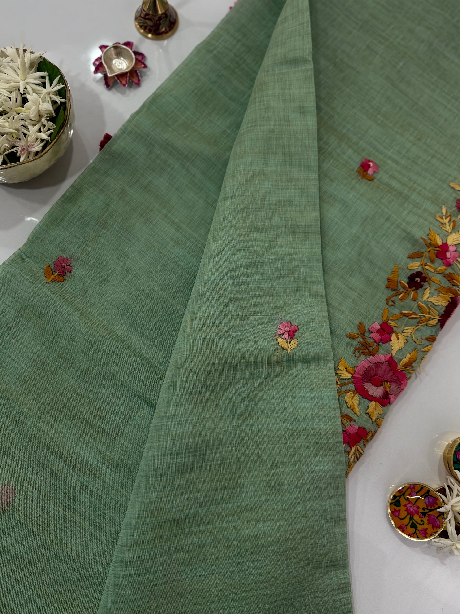 Green fabric with floral embroidery on a white surface