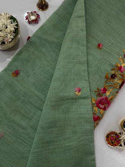 Green fabric with floral embroidery on a white surface