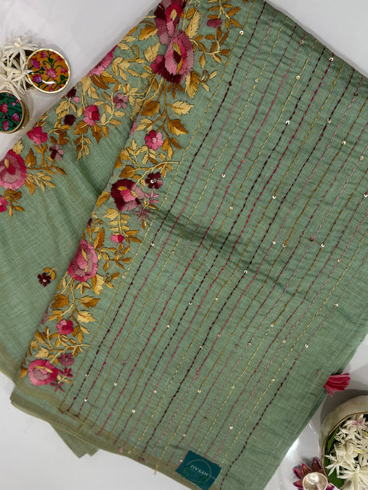 Green fabric with floral embroidery on a white surface