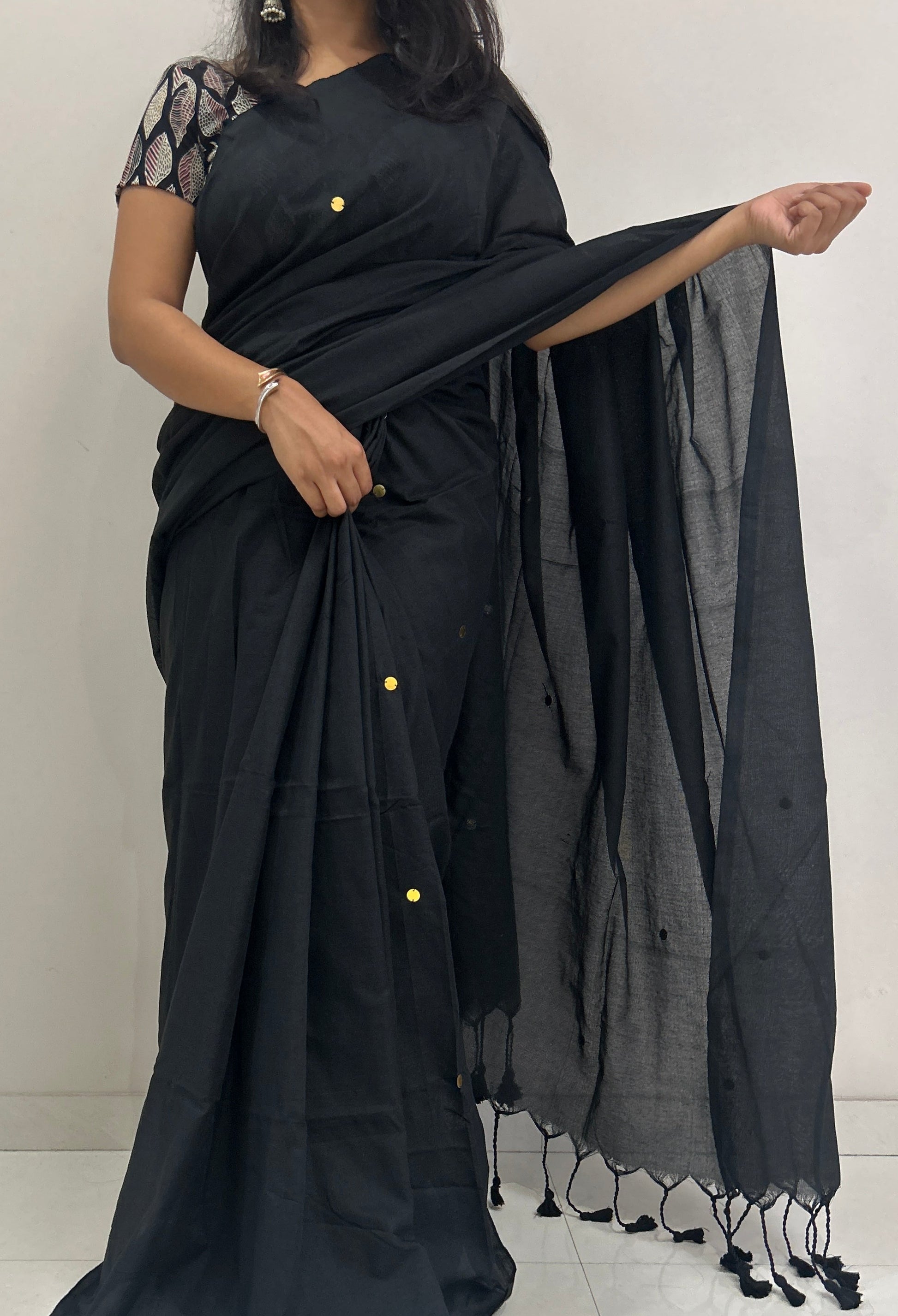 Woman wearing a black saree with a plain background