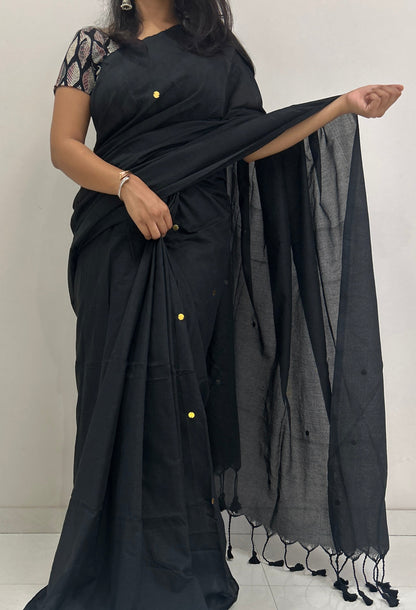 Woman wearing a black saree with a plain background